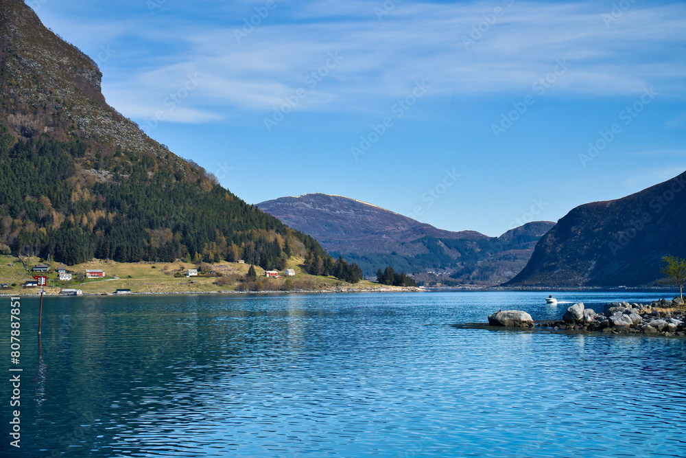 Fjord with mountains on horizon. Water glistens in the sun in Norway. Landscape