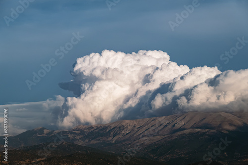 Huge cumulus cloud on top of mountain against dramatic moody sky, landscape