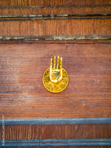 Old brass doorknob shaped as Abhayamudra gesture, symbolizing fearlessness and reassurance, outstretched hand beckoning viewers with good intentions, inviting strangers, evoking peace and protection. photo