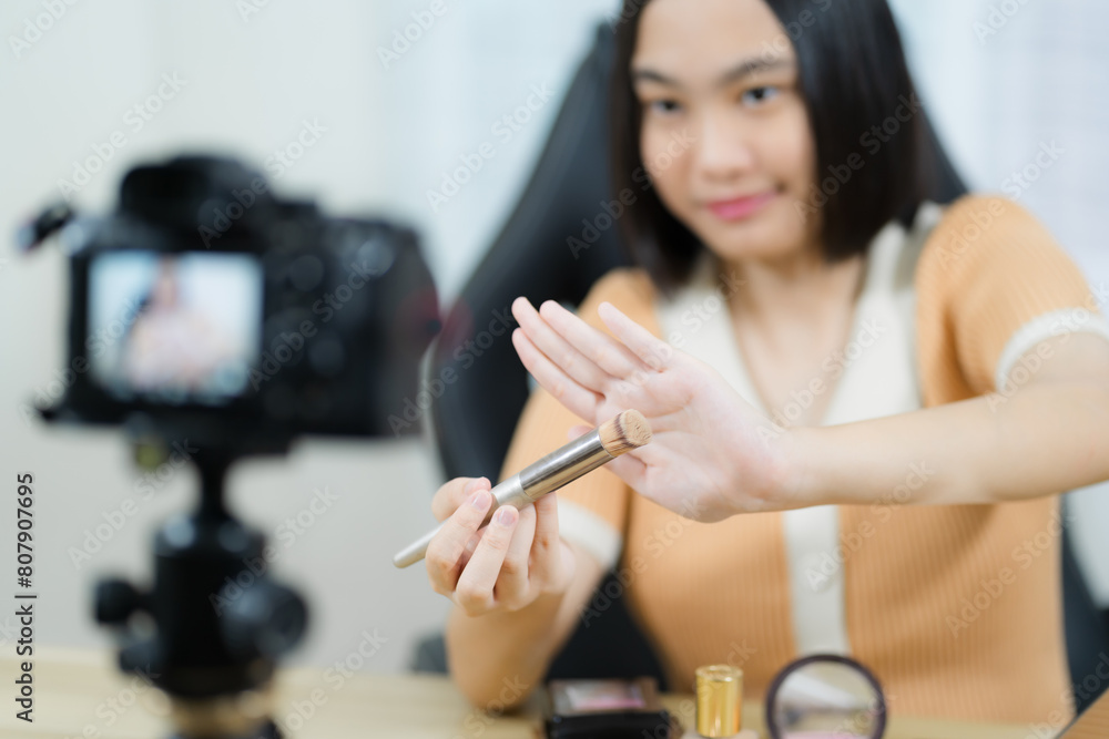 Young beautiful Asian girl, professional or blogger, recording makeup to share on social media.