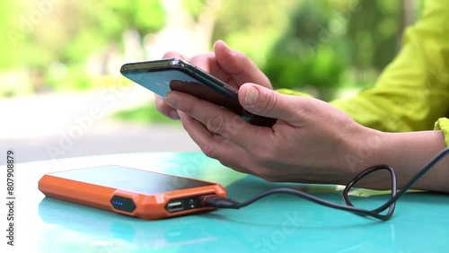 4k footage ogf Female hands using mobile phone while charging it with a portable power bank photo