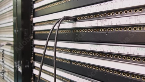 Patch panel in broadcast center, black SDI cable connected into BNC jack of back commutation panel of telecommunication video switcher with lot of jacks in broadcast technical room of TV channel photo