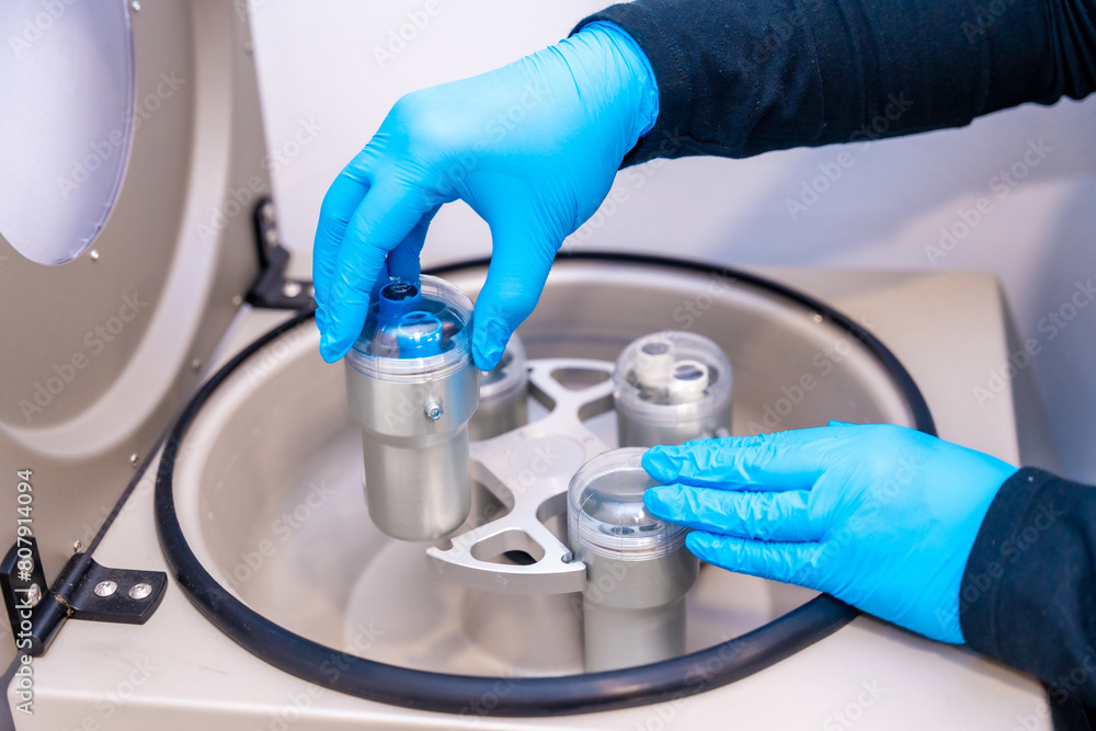 Lab worker placing test tubes with blood samples in centrifuge Lab worker placing test tubes with blood samples in centrifuge