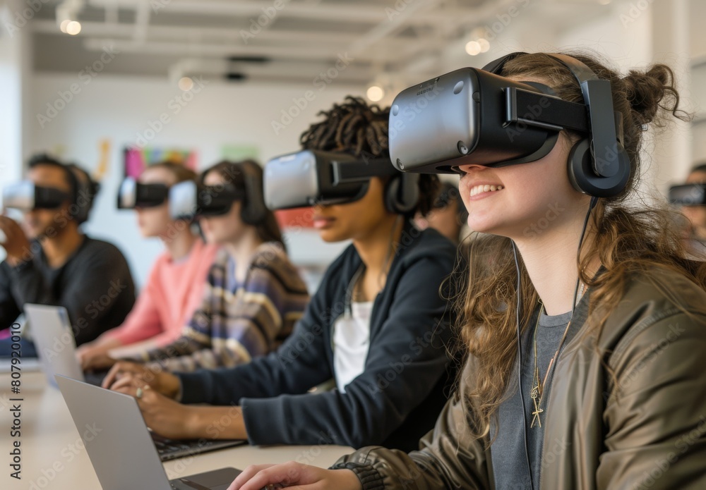 A group of students wearing VR headsets, with one student using the technology to interact and engage in an educational experience while others watch from their laptops or smartph A group of students wearing VR headsets, with one student using the technology to interact and engage in an educational experience while others watch from their laptops or smartph