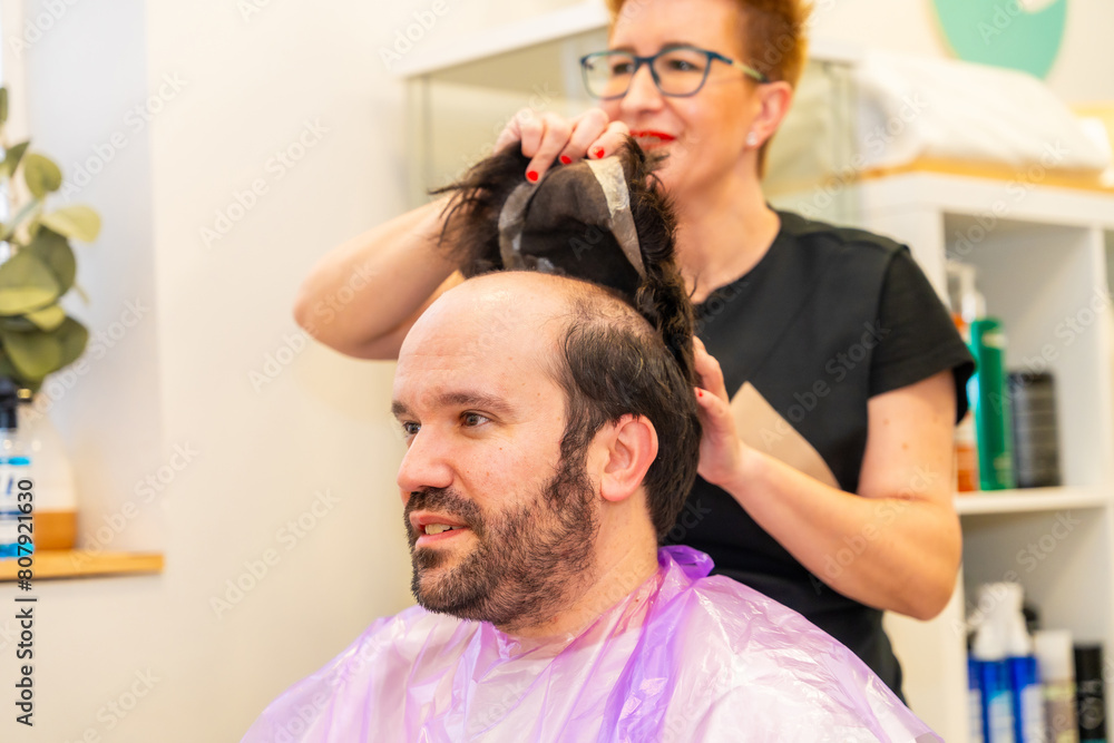 Hairdresser removing the capillary prosthesis from a client