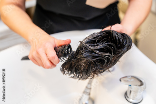 Foto Hairdresser combing and cleaning a natural capillary prosthesis