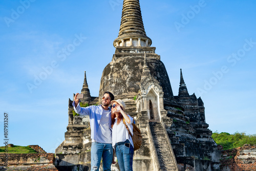 young couple tourist taking selfie while visiting at Wat Phra Si Sanphet, Ayutthaya historical park, Thailand. concept of historical tourism south east asia, travelling, destination Thailand