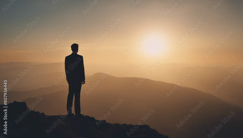 silhouette of a businessman in a suit standing on a high mountain peak 
