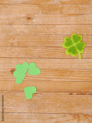 A wooden table with a green shamrock and four hearts on it