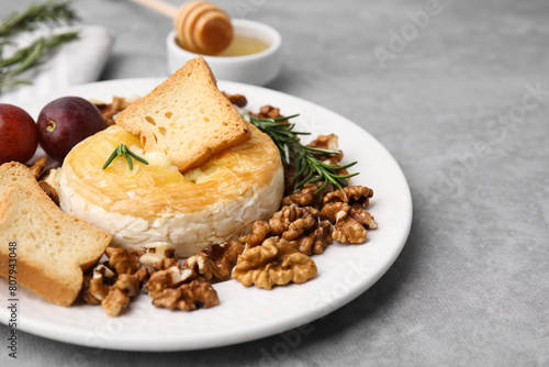 Tasty baked camembert and different products on gray table, closeup