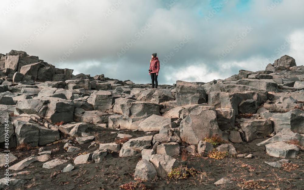 Girl standing between large boulders. Hiker with anorak in a rocky land. Adventure, exploration, tourism, iceland, wilderness.
