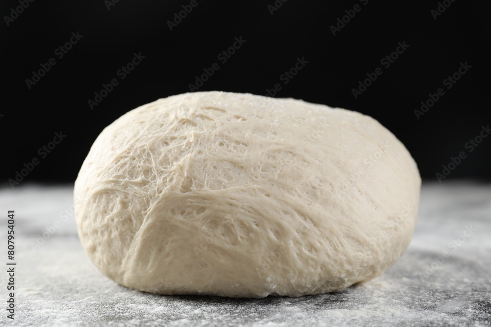 Raw homemade dough and flour on black table Raw homemade dough and flour on black table