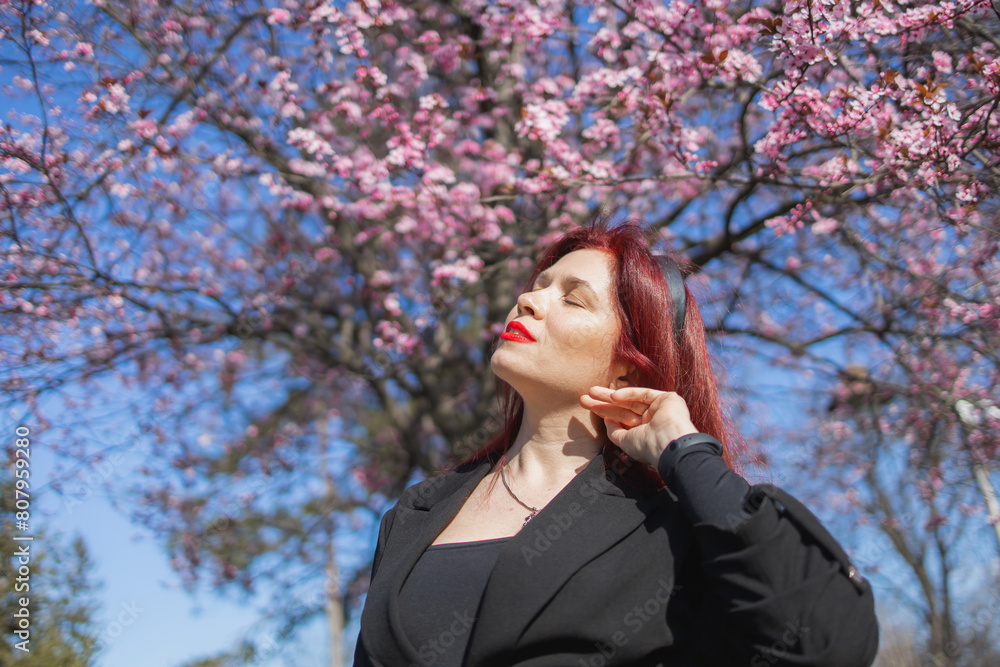 Woman with cherry flowers surrounded by blossoming trees copy space. Beauty and seasonal change and spring bloom season concept. Woman with cherry flowers surrounded by blossoming trees copy space. Beauty and seasonal change and spring bloom season concept.