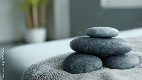 Gray zen pebble hot stones with towel on massage table. Treatment concept with hot stones. Harmony  balance and meditation concept set  spa  relaxation.