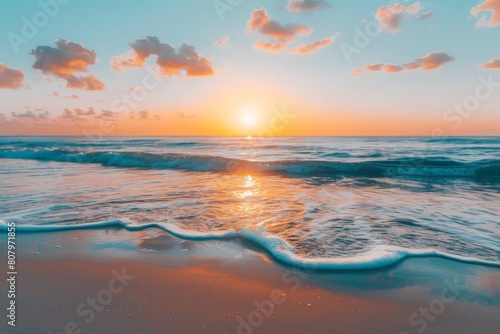 Waves gently rolling onto shore under a dramatic sunset with vibrant orange hues reflecting off the sea