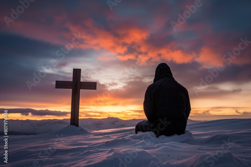 Silhouetted individual kneeling before a cross in a snowy landscape, suggesting contemplation at dusk