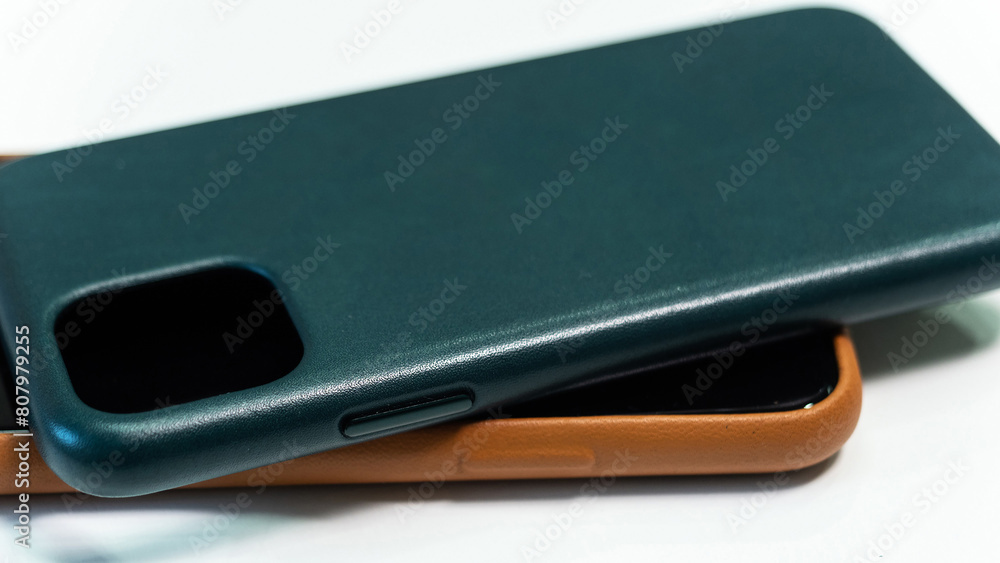 Two cell phone cases, one brown and one green, are stacked on top of each other Two cell phone cases, one brown and one green, are stacked on top of each other