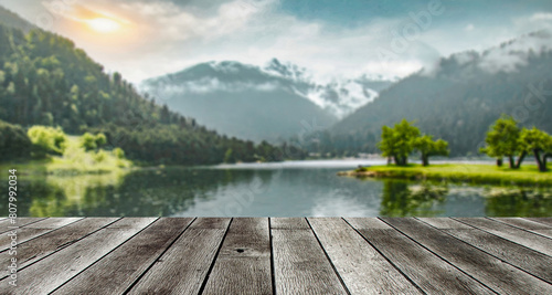 table background of free space for your decoration and blurred landscape of mountains.Blue sky with sun light and green small leaves.