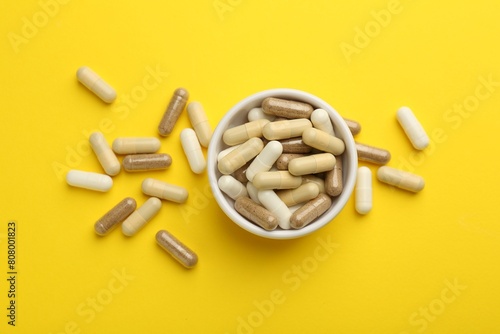 Obraz na płótnie Different vitamin capsules on yellow background, flat lay
