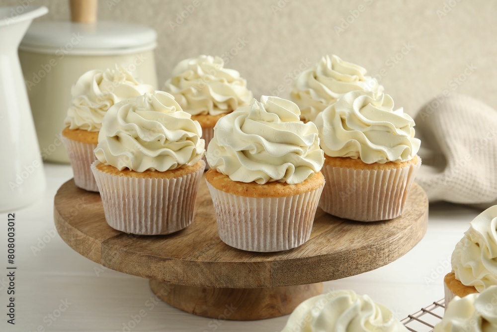 Tasty vanilla cupcakes with cream on white wooden table Tasty vanilla cupcakes with cream on white wooden table