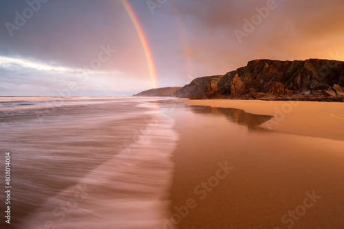 Sandymouth Bay, early morning light and rainbow at low tide, north Cornwall, UK. December 2020.  photo