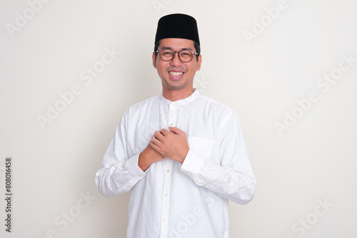 Moslem Asian man smiling at the camera with both hand touching his chest photo