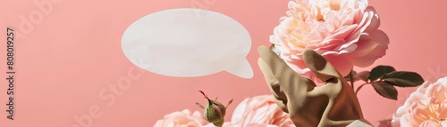 A hand wearing a gardening glove holding a flowershaped speech bubble, against a blooming rose background, ideal for gardeners or floral shops photo