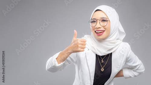 Portrait of Muslim woman in office attire and wearing a hijab. Corporate  or business people concept. Isolated on grey background. 16:9 ratio with copyspace on one side of the banner