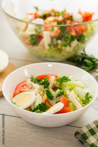 fresh vegetable salad, cabbage, tomatoes in a bowl on a wooden table