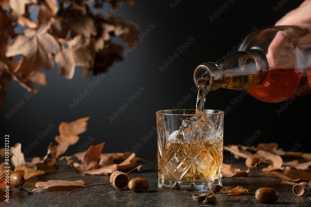 Whiskey with ice on a black table with dried-up oak leaves. Whiskey with ice on a black table with dried-up oak leaves.