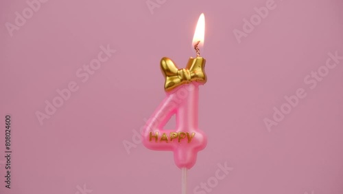 Burning pink birthday candle with golden bow and word happy on pink background, number 4.