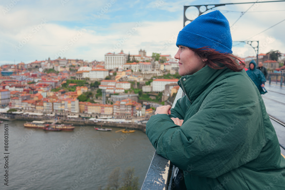 Woman overlooking the picturesque Douro river and colorful cityscape of Porto, Portugal on overcast day