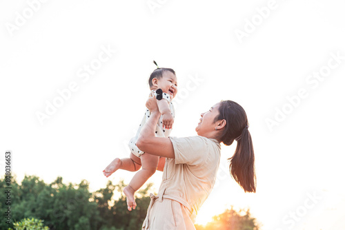 mother and child,happy harmonious family outdoors. mother throws baby up, laughing and playing in the summer on the nature