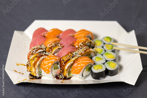 Tasty Colorful assorted Set of different type Sushi with chopsticks. Dinner in Japanese style. Healthy food. Filadelfia and Maki sushi rolls with Avocado, Tuna, Salmon, fish and Prawns.