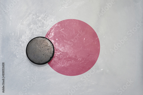 old hockey puck is on the ice with national flag of japan . photo