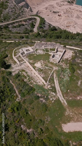 Drone view of the ruins of an old castle on top of a mountain and a view of a beautiful bay hidden between the mountain slopes in Rakalj, Croatia photo