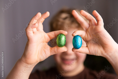 child holding up Easter eggs between fingers photo