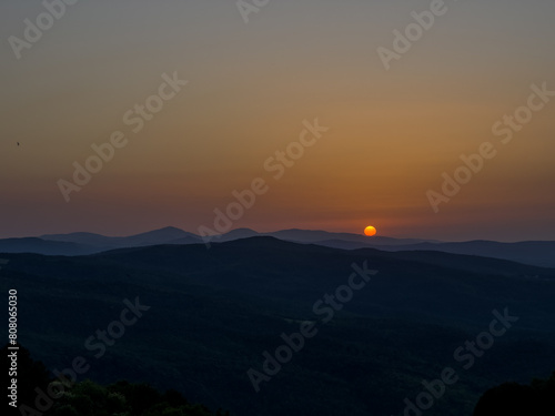 tarcza słońca dotykająca wierzchołków gór, koniec dnia w Toskanii © Kamil_k2p