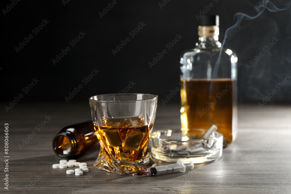 Alcohol and drug addiction. Whiskey in glass, syringe, pills and cigarettes on wooden table Alcohol and drug addiction. Whiskey in glass, syringe, pills and cigarettes on wooden table