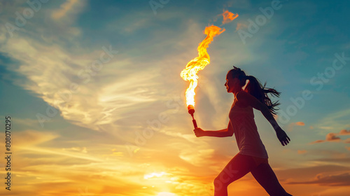 Female athlete runs and carrying torch fire with sunset sky background. For olympics games concept.