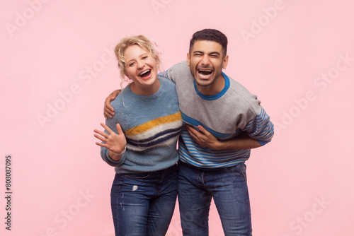 Portrait of extremely happy woman and man standing together laughing out loud hearing funny joke positive emotions. Indoor studio shot isolated on light pink background.
