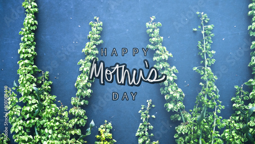Happy Mothers Day graphic background with greeting and green flowers on blue color backdrop.