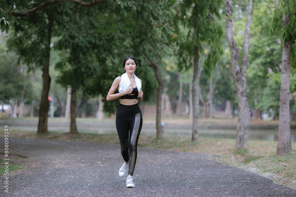 Young Asian woman running hard on the street at the park after daily exercise. Jogging to keep fit on a warm summer morning. Young Asian woman running hard on the street at the park after daily exercise. Jogging to keep fit on a warm summer morning.