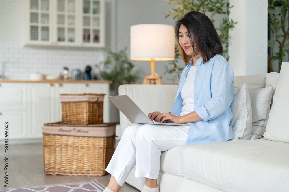 adult attractive asian female working at home hand use laptop checking search schedule working process planning report with leisure relax on sofa in living room with morning light peaceful moment adult attractive asian female working at home hand use laptop checking search schedule working process planning report with leisure relax on sofa in living room with morning light peaceful moment