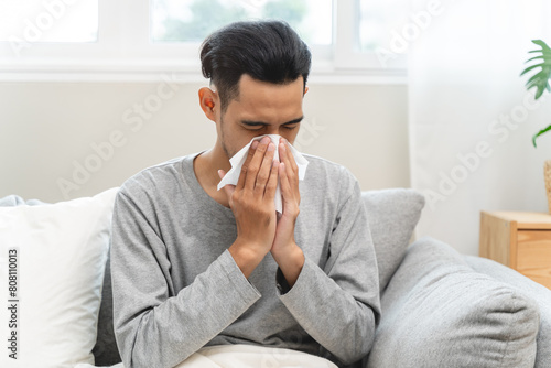 Seasonal cold sickness in people concept, Sick asian man looking at thermometer during measuring his body temperature feel exhausted and headache from fever.