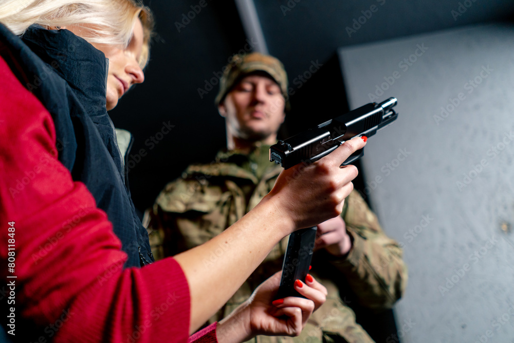 Fototapeta premium low shot in a professional shooting range military man tells and shows a girl the correct stance with a pistol is