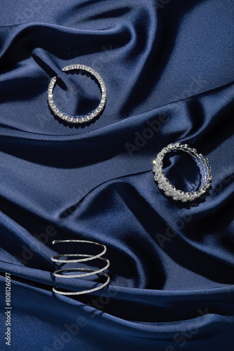 Bracelets with diamonds on a background of blue silk. Expensive jewelry. Natural gems. Top view. Space for text.