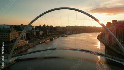 Drone flies sideways along Millennium Bridge in Newcastle Gateshead as the sun rises on an autumn morning. The Baltic centre is seen behind photo