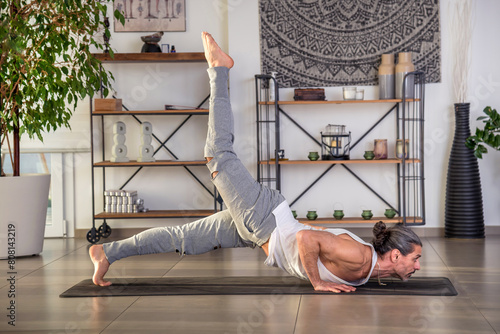 Man doing hatha yoga on mat in hall photo