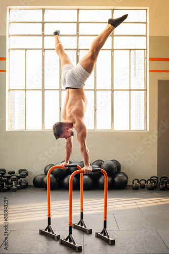 Strong man performing Straddle handstand on parallel bars calisthenic